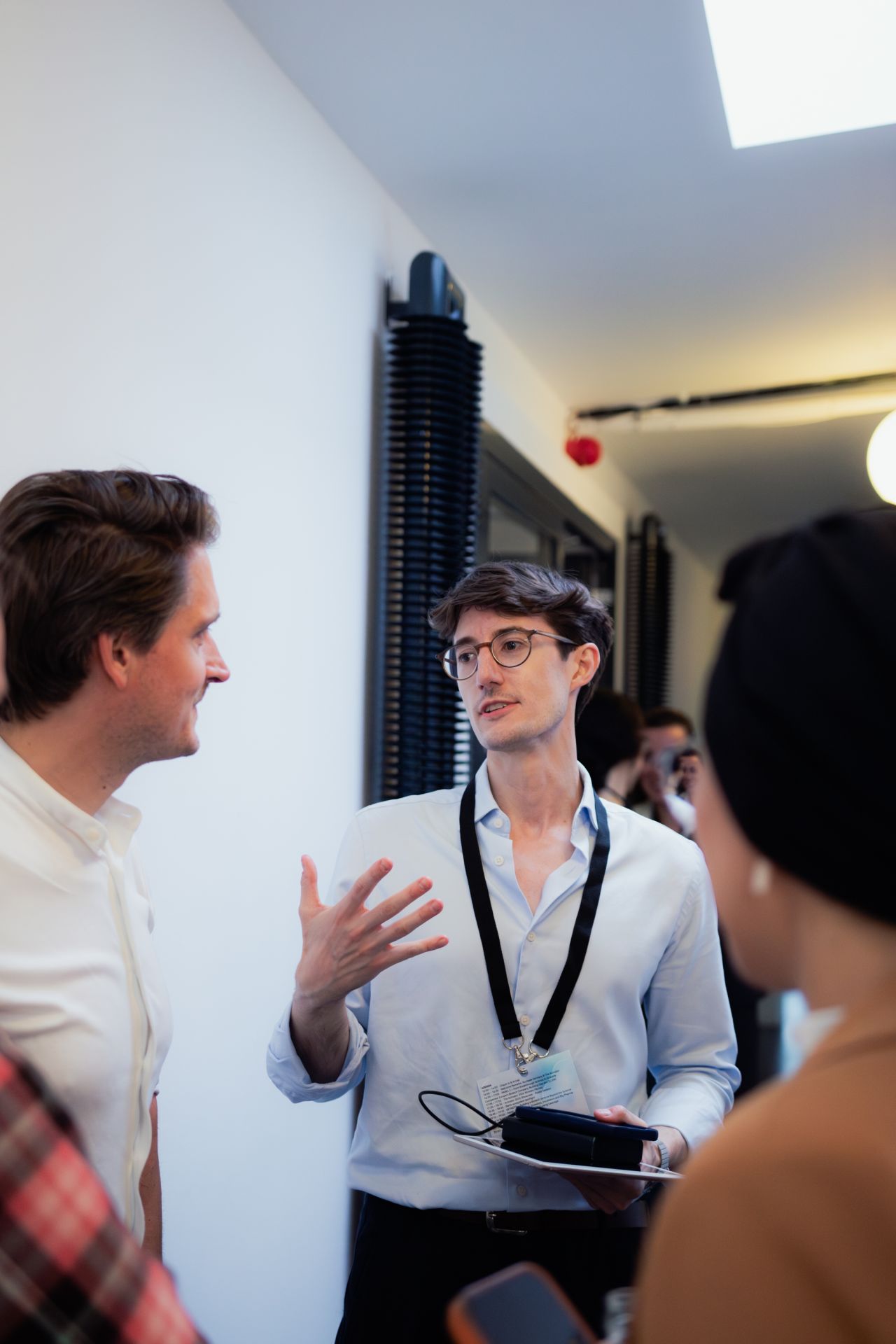 David explaining something on a tablet to two colleagues during a conference break