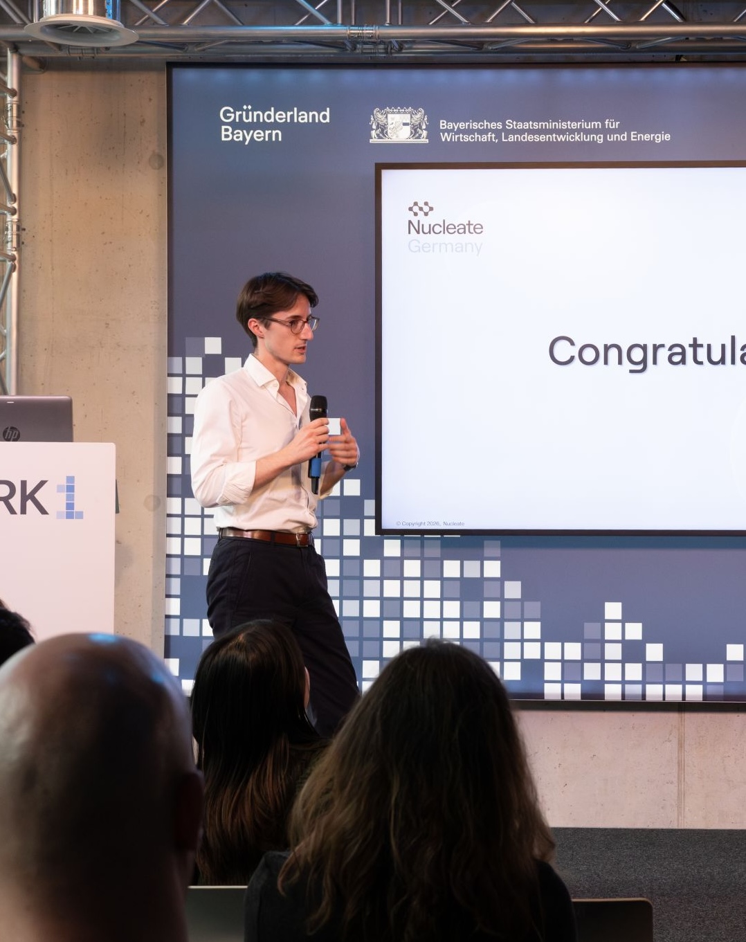 David speaking to an audience from a stage at a Nucleate Germany event